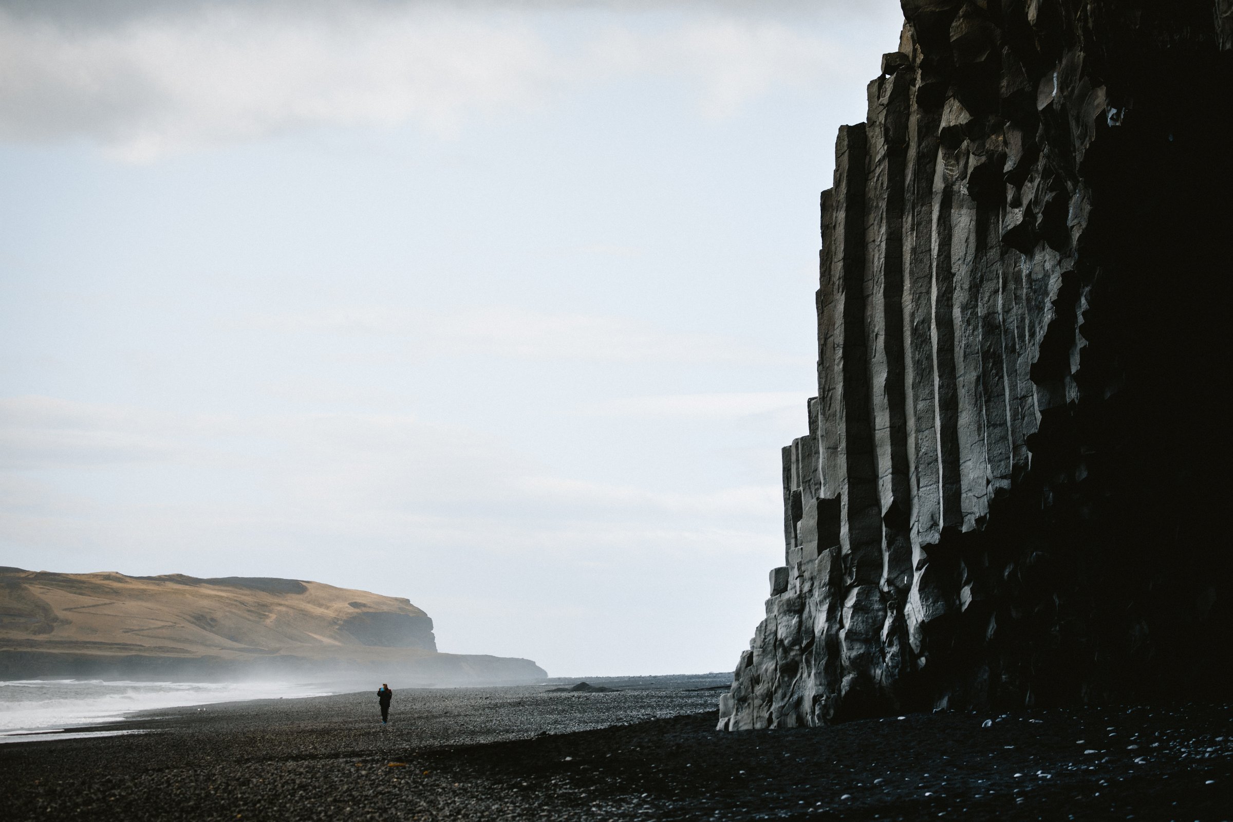 Black sand beach of Reynisfjara in Iceland, with dramatic basalt columns and Reynisdrangar rock formations rising from the ocean.