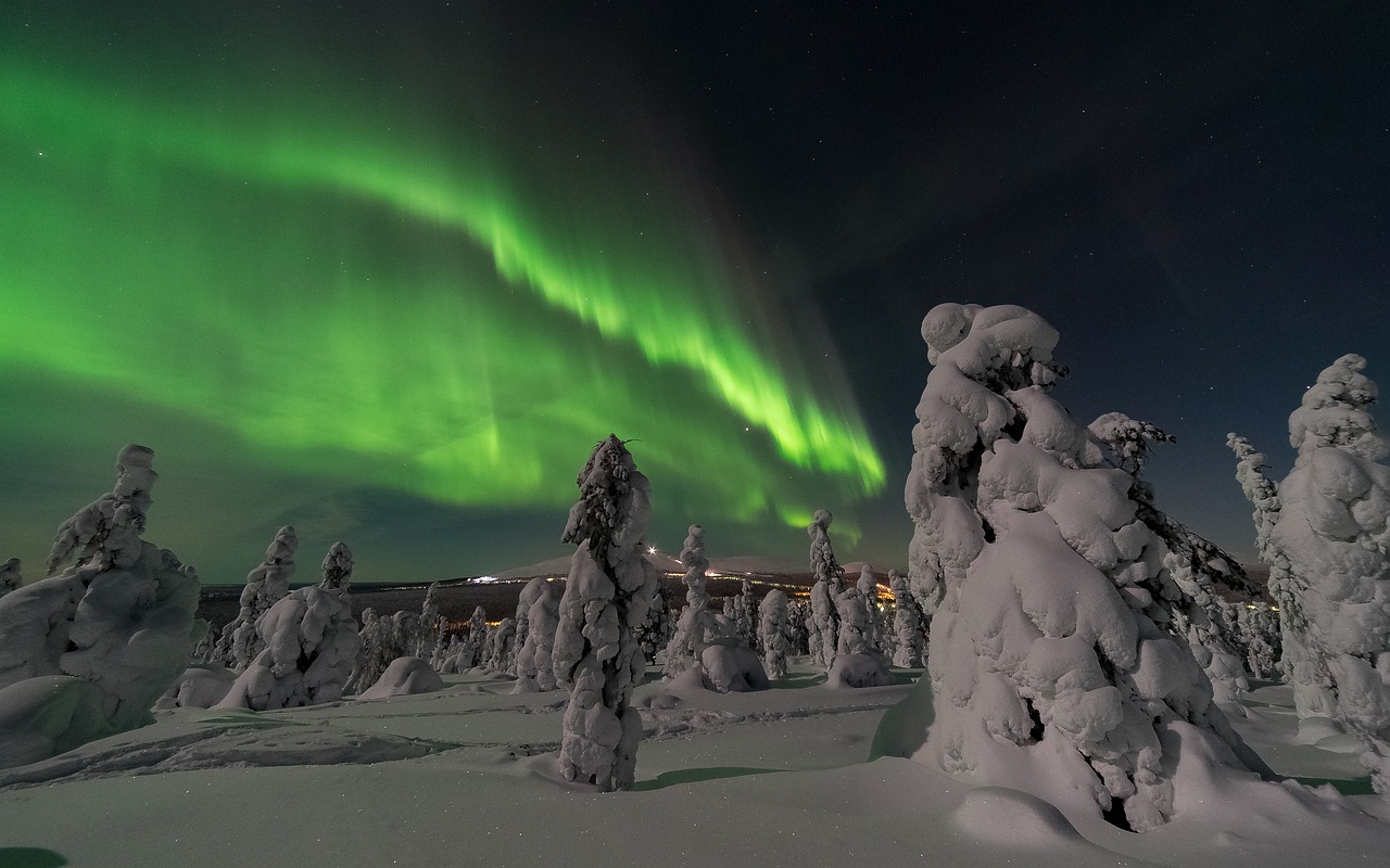 A breathtaking display of the Aurora Borealis, or Northern Lights, dancing across the night sky in Finland, with vibrant green and purple hues illuminating the landscape.