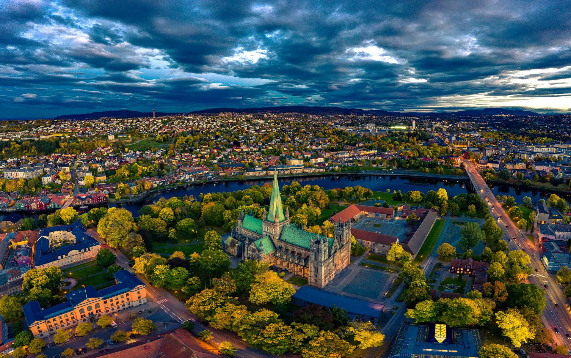 Aerial view of Trondheim, Norway, showcasing the city's historic architecture, including the iconic Nidaros Cathedral, surrounded by the meandering Nidelva River and a patchwork of colorful buildings and streets.