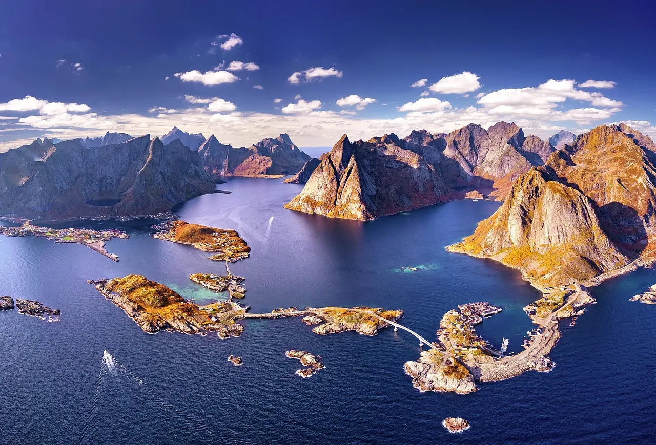 Aerial view of Norway's Lofoten Islands, featuring rugged mountains, clear waters, and picturesque villages.